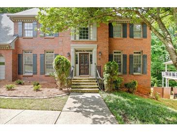Beautiful brick home featuring a decorative wood front door, manicured landscaping, and stone steps at 2355 Twelvestones Dr, Roswell, GA 30076