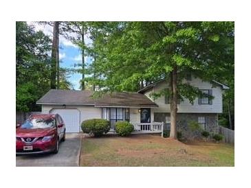 Charming two-story home with a well-maintained lawn, mature trees, and a visible garage at 6193 Charring Cross Ct, Lithonia, GA 30058