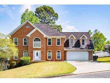Traditional brick home with well-maintained landscaping, attached garage, and bright white trim against a vivid blue sky at 2253 Carrington Dr, Ellenwood, GA 30294