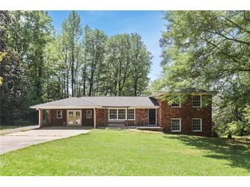 Charming red brick home with a covered carport, lush green lawn, and mature trees at 3007 Octavia Cir, Marietta, GA 30062