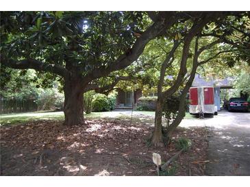 Charming home with mature trees and a lush front lawn, partially obscuring the brick facade at 5170 Chamblee Dunwoody Rd, Atlanta, GA 30338
