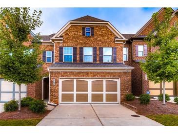 Charming brick townhome featuring a two-car garage and manicured landscaping, offering a welcoming curb appeal at 4150 Cedar Bridge Walk, Suwanee, GA 30024