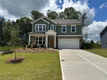 Inviting two-story home with a green exterior, stone accents, manicured lawn, and an attached two-car garage at 5377 Heron Bay Blvd, Locust Grove, GA 30248