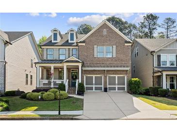 Beautiful two-story brick home featuring a welcoming front porch, manicured landscaping, and a two-car garage at 127 Marlow Dr, Woodstock, GA 30188