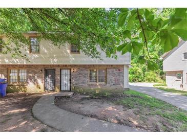 Inviting townhouse with a brick facade, covered entry, and mature trees at 1432 Forest Villa Dr, Conyers, GA 30012