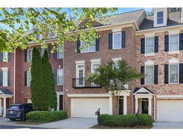 Charming brick townhome featuring black shutters, a two-car garage, and manicured landscaping at 478 Vinings Estates Se Dr # B02, Smyrna, GA 30126