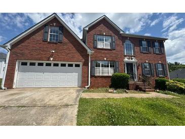 Traditional two-story brick home with an attached two-car garage and well-manicured landscaping at 5704 Winchester Pl, Lithonia, GA 30038