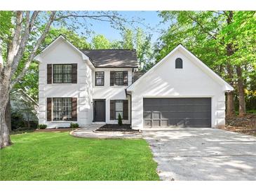 Charming two-story home with white brick, black shutters, lush lawn, and a two car garage at 275 Carriage Chase, Fayetteville, GA 30214