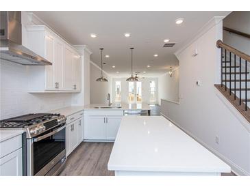 Bright kitchen boasts white cabinets, stainless steel appliances, and a spacious island at 118 Iveybrooke Ln # 64, Alpharetta, GA 30009