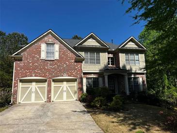 Charming two-story home featuring a brick facade, two-car garage, and manicured landscaping at 5679 Coopers Glen Ct, Mableton, GA 30126