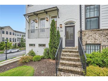 Charming townhome entrance with brick stairs, white brick facade, and inviting wrought iron details at 1780 Morningtide Ne Ln, Atlanta, GA 30324