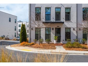 Charming townhome featuring a painted brick facade, black framed windows and tasteful landscaping at 472 Burton Dr, Alpharetta, GA 30009
