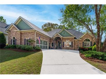 Charming brick home with lush landscaping, long driveway, and a welcoming facade under a bright blue sky at 2111 Democracy Dr, Buford, GA 30519