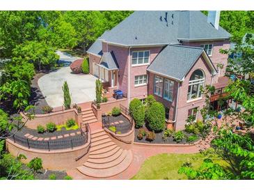 Expansive brick backyard featuring a landscaped terrace, manicured shrubs and lawn, and a multilevel deck at 2644 Nutwood Trce, Duluth, GA 30097