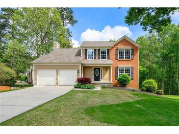 Charming two-story home with a manicured lawn, two-car garage, and traditional architectural details at 7260 Foxberry Ct, Cumming, GA 30041