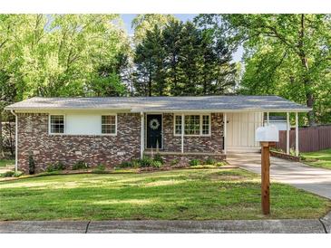 Charming brick home with a well-manicured lawn, mature trees, and welcoming front porch and tasteful landscaping at 2079 Nancy Se Cir, Smyrna, GA 30080