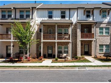 Charming townhome with brick facade, covered porch, and second-story balcony offers inviting curb appeal at 4065 Holland Grove Rd, Lawrenceville, GA 30044
