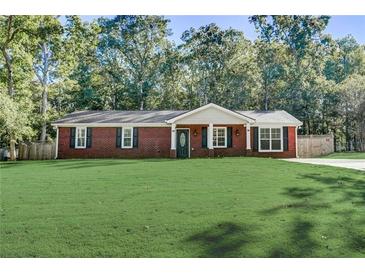 Charming red brick home with a well-manicured front yard and mature trees in the background at 715 Cowan Rd, Covington, GA 30016