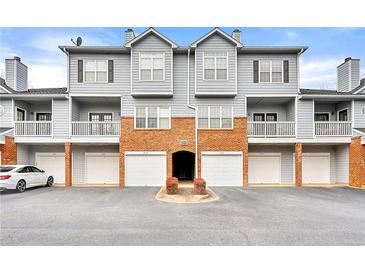 Exterior view of a three story condo building with brick facade, garages and balconies at 406 Vinings Forest Se Cir, Smyrna, GA 30080