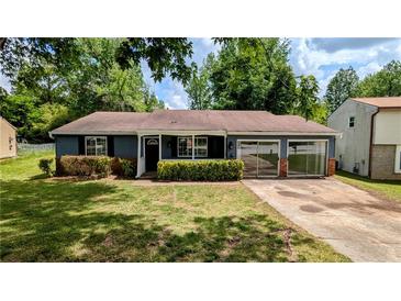 Charming single-story home featuring a well-manicured lawn, blue siding, and an inviting covered front porch at 5266 Long Green Ln, Stone Mountain, GA 30088