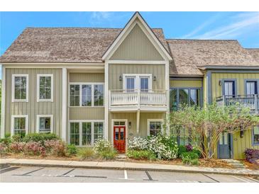 Charming two-story townhome with a cozy balcony, red front door and beautiful landscaping at 11189 Serenbe Ln, Chattahoochee Hills, GA 30268