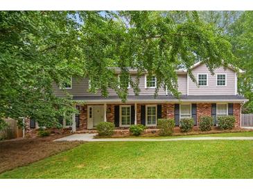 Charming two-story home with brick and siding exterior, manicured lawn, and mature trees at 3932 Granger Dr, Brookhaven, GA 30341
