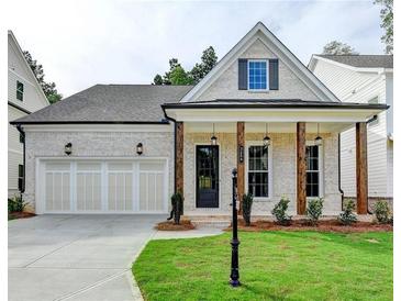 Charming home featuring a two-car garage, a welcoming front porch with wooden beams, and a well-manicured lawn at 2381 Siskin Square Rd, Duluth, GA 30096