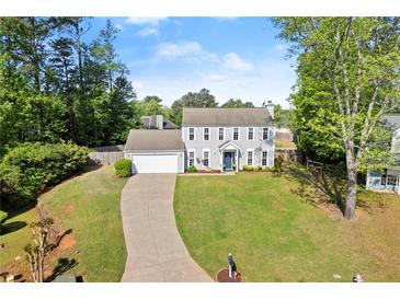 Charming two-story home featuring a well-manicured lawn, attached garage, and welcoming blue front door at 660 Cranberry Ct, Roswell, GA 30076