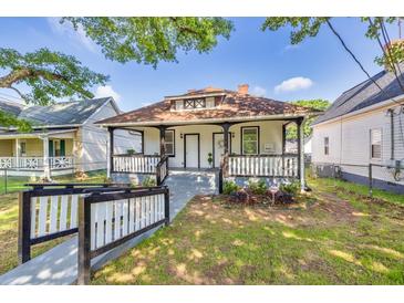 Charming white home with a cozy front porch and well-maintained lawn and attractive landscaping at 11 Poplar St, Porterdale, GA 30014