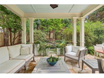Covered patio featuring stone floor, comfortable seating, and a view of the lush garden at 1153 Brookhaven Commons Ne Dr, Brookhaven, GA 30319