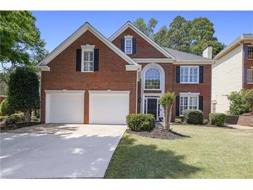 Charming two-story brick home with a well-manicured lawn, two-car garage, and a classic front door at 4044 Kenway Se Pl, Smyrna, GA 30082