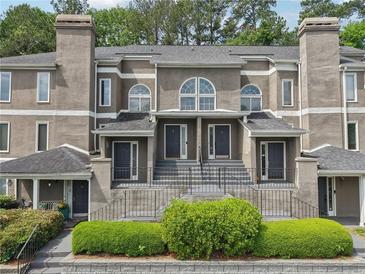 Attractive townhome with neutral stucco exterior, arched windows, dark doors, and manicured landscaping at 44 Saint Claire Ne Ln, Atlanta, GA 30324