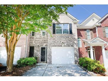 Charming brick townhome featuring a one-car garage, black door and shutters, and a well-maintained front yard at 2263 Leicester Se Way, Atlanta, GA 30316