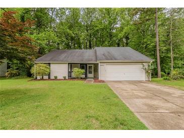 Well-maintained single-story home with a green lawn and a driveway leading to a garage at 964 Chapman Ln, Stone Mountain, GA 30088