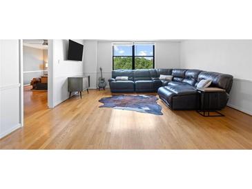 Spacious living room with hardwood floors, a large window, and a comfortable leather sectional sofa at 2965 Pharr Court South Nw # 1-817, Atlanta, GA 30305