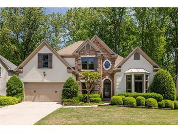 Charming home with a manicured lawn, beautiful landscaping, and a stone-accented facade at 150 Park Creek Dr, Alpharetta, GA 30005