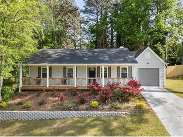 Charming single-Gathering home featuring a cozy front porch and a well-maintained lawn with blossoming rose bushes at 874 Fox Valley Dr, Stone Mountain, GA 30088
