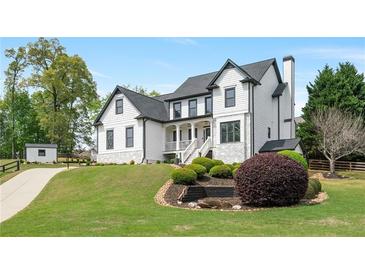 Beautiful two-story home with white siding, black roof, a landscaped yard and a charming front porch at 4030 Scenic View Ct, Cumming, GA 30028