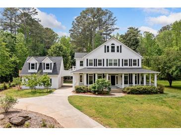 Charming two-story white farmhouse with a large covered front porch and meticulously maintained landscaping at 10192 Shallowford Rd, Roswell, GA 30075
