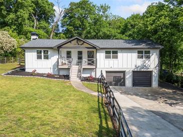 Charming white two-story home with manicured lawn and an inviting front porch and 2-car garage at 369 Arnold Mill Rd, Woodstock, GA 30188