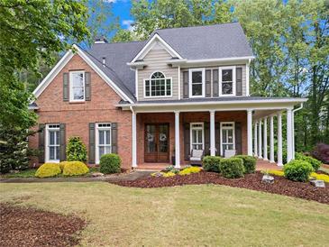Charming two-story brick home with a covered front porch and beautifully landscaped front yard at 4592 Planters Hill Dr, Powder Springs, GA 30127