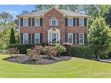 Beautiful brick home with manicured lawn, black shutters, and classic architectural details at 4257 Edgewater Nw Dr, Kennesaw, GA 30144