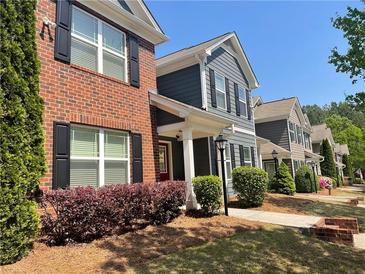 Charming townhomes featuring brick and siding exteriors, complemented by lush landscaping and inviting walkways at 487 Cypher Dr, Suwanee, GA 30024