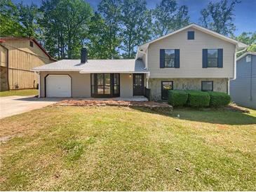 Charming split-level home featuring a well-maintained lawn, gray siding, and a one car garage at 1950 Matthew Way, Lithonia, GA 30058