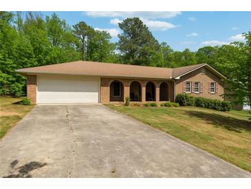 Charming brick ranch home featuring a two-car garage and a long driveway, surrounded by mature trees at 2944 Williams Pl, Snellville, GA 30078