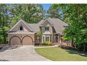 Charming two-story home featuring a well-manicured lawn, arched windows, and an attached two-car garage at 1336 Amberwood Dr, Woodstock, GA 30189