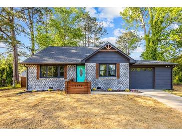 Charming bungalow featuring a brick exterior, dark roof, and a vibrant teal front door at 1554 Cardinal Rd, Jonesboro, GA 30238