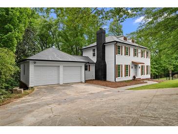 Charming two-story home with white siding, dark shutters, a black chimney and a two-car garage at 6659 Manoleta Dr, Lithonia, GA 30038
