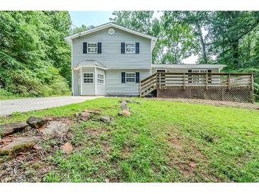 Charming two-story home with a wooden deck, gray siding, black shutters, and mature trees at 270 Hunt Ridge Dr, Stockbridge, GA 30281