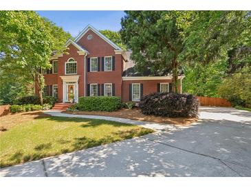 Beautiful two-story brick home with a well-manicured lawn and mature trees, creating a welcoming curb appeal at 5100 Sunset Maple Trl, Lilburn, GA 30047